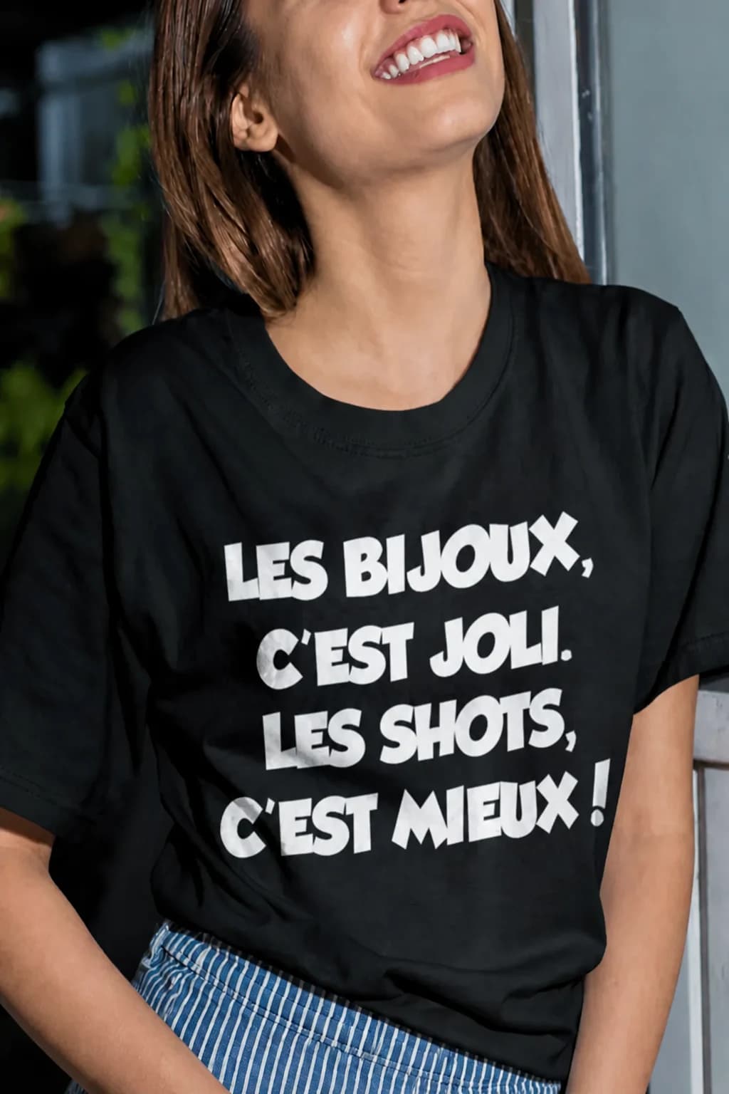 T-shirt noir porté par une femme avec le texte blanc « Les bijoux, c'est joli. Les shots, c'est mieux ! »