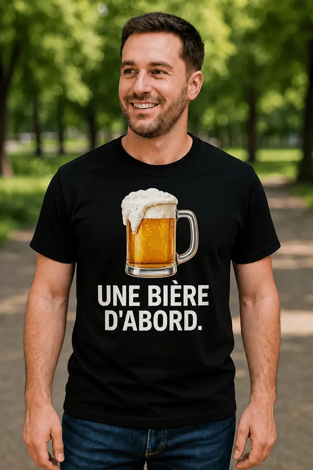 Homme souriant en t-shirt noir avec une chope de bière mousseuse et le texte blanc « Une bière d'abord »