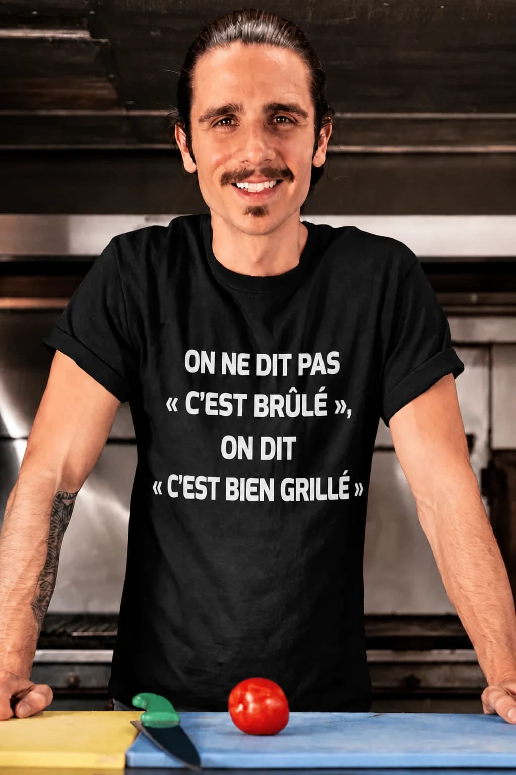 Homme souriant en cuisine portant un t-shirt noir à message humoristique sur les grillades