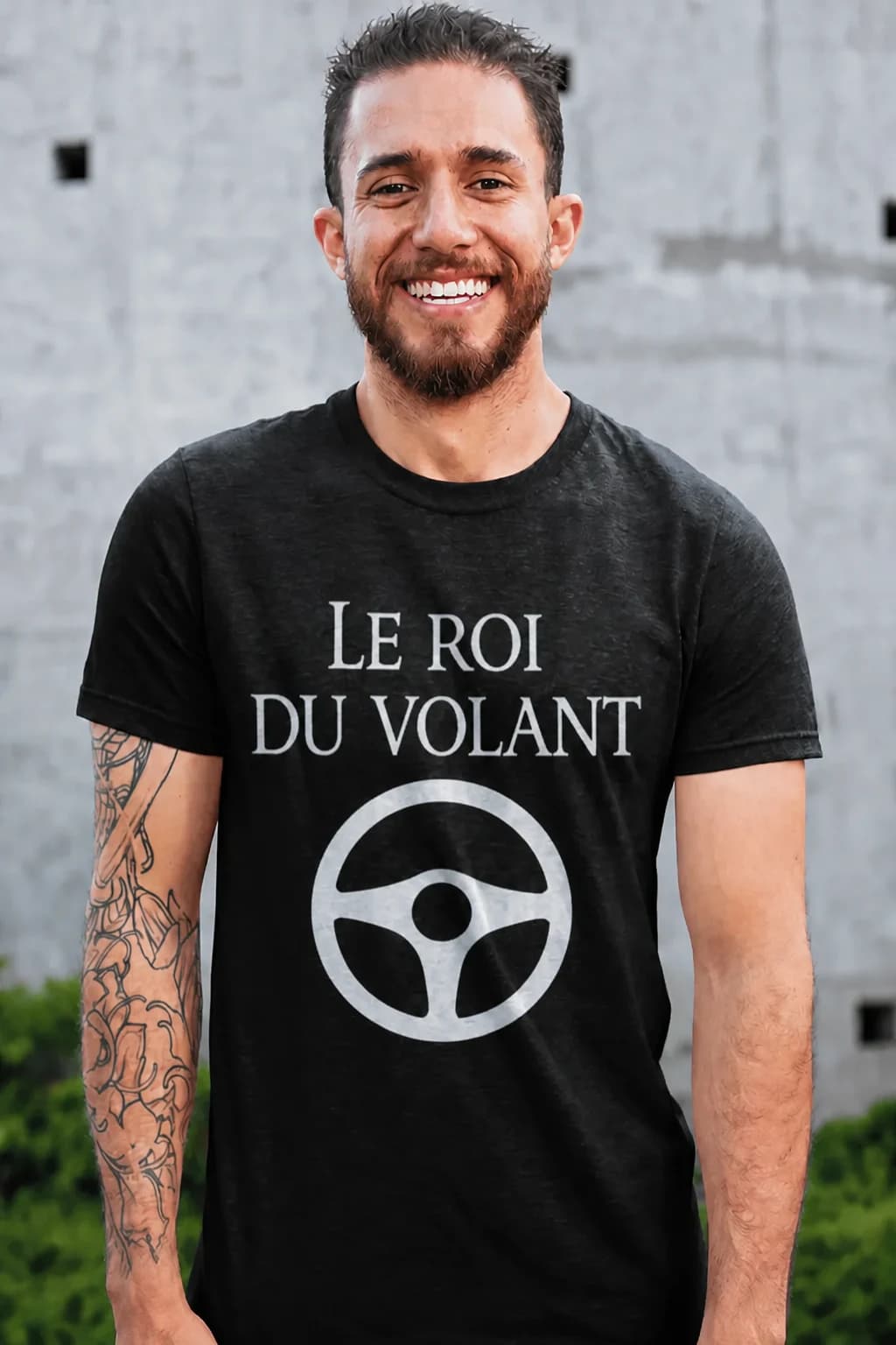 Homme souriant en t-shirt noir avec le texte « Le roi du volant » et un volant de voiture stylisé en blanc