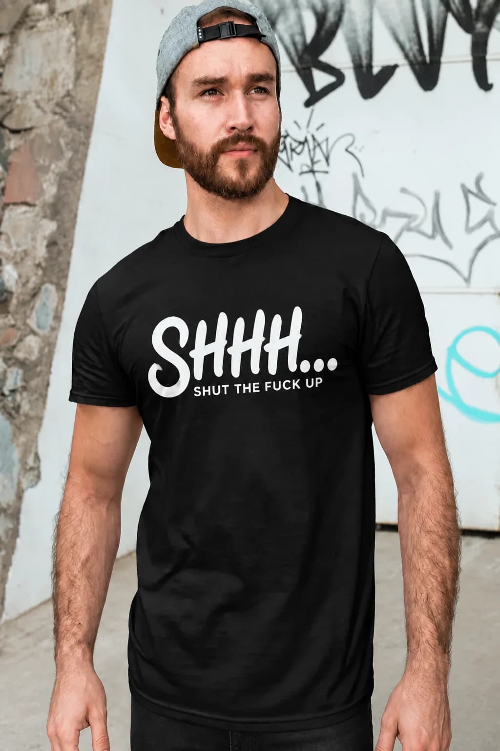 Homme barbu en t-shirt noir avec « Shhh » écrit à la main et le texte « shut the fuck up » en dessous
