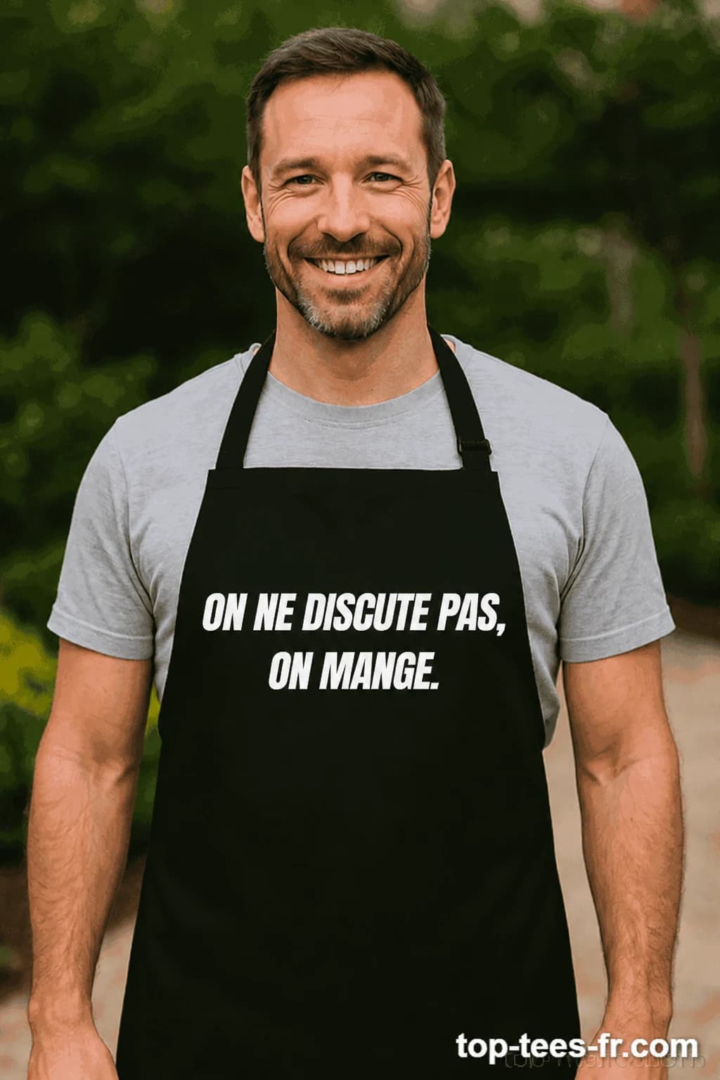 Homme souriant en tablier noir imprimé « On ne discute pas, on mange. » en lettres blanches