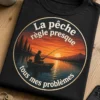T-shirt pêche avec badge circulaire au coucher du soleil, silhouette de pêcheur en barque sur lac calme et slogan La pêche règle presque tous mes problèmes